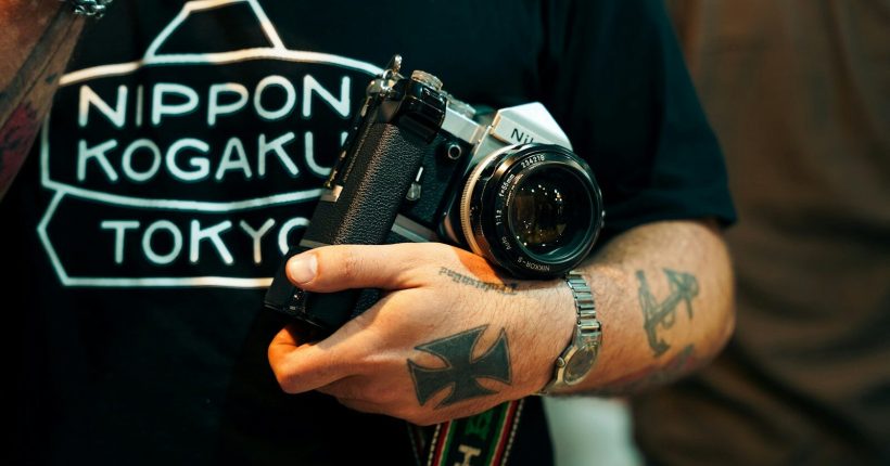Man with tattoos holds vintage camera