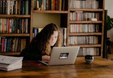 woman in black long sleeve shirt using macbook air on brown wooden table