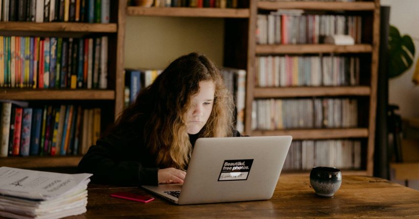 woman in black long sleeve shirt using macbook air on brown wooden table