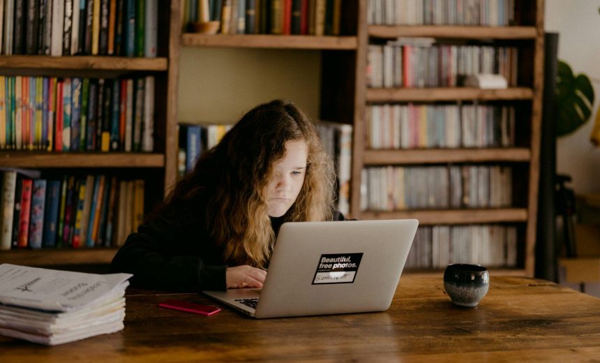 woman in black long sleeve shirt using macbook air on brown wooden table