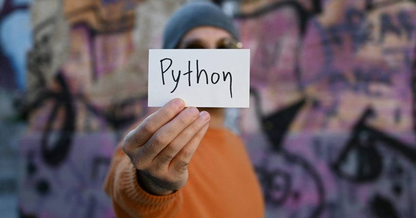 a man holding up a piece of paper with the word python written on it