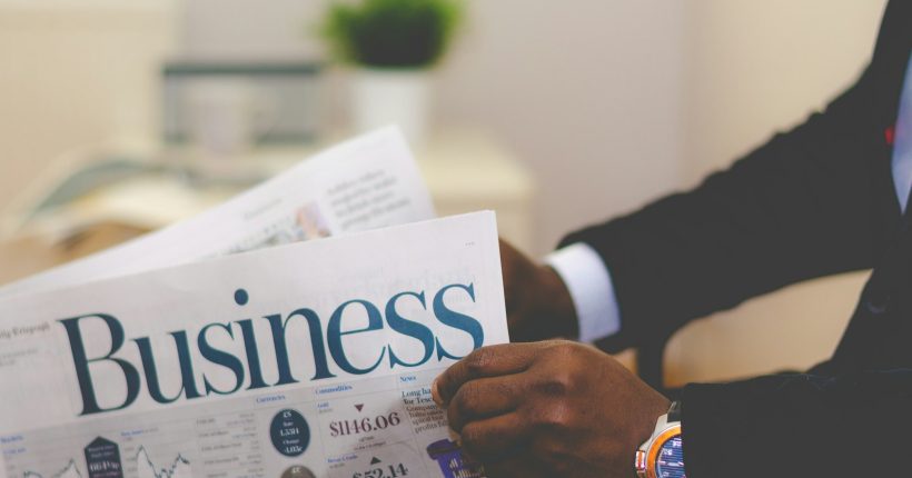 person wearing suit reading business newspaper