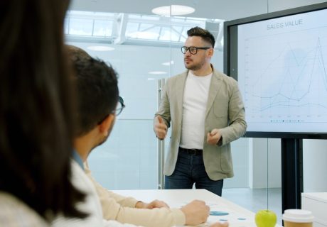 Man presenting data on a large screen to colleagues.