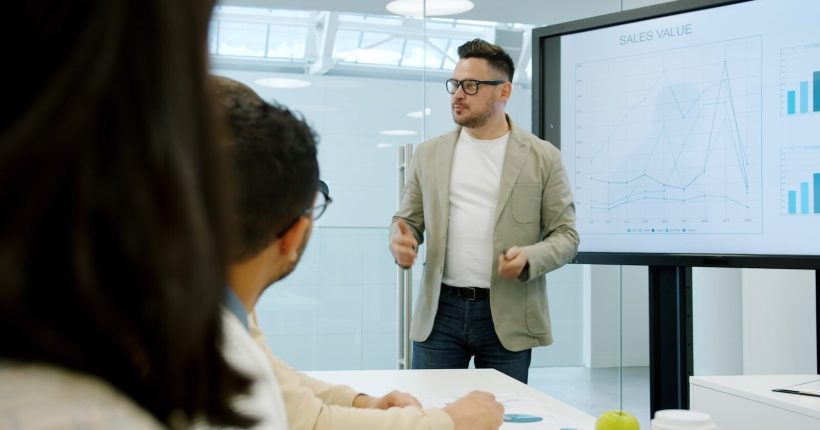 Man presenting data on a large screen to colleagues.