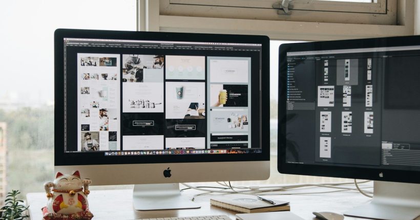 Two monitors setup next to each other on a computer desk.