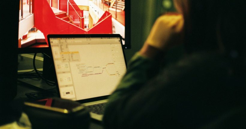 person wearing black jacket in front of flat screen computer monitor
