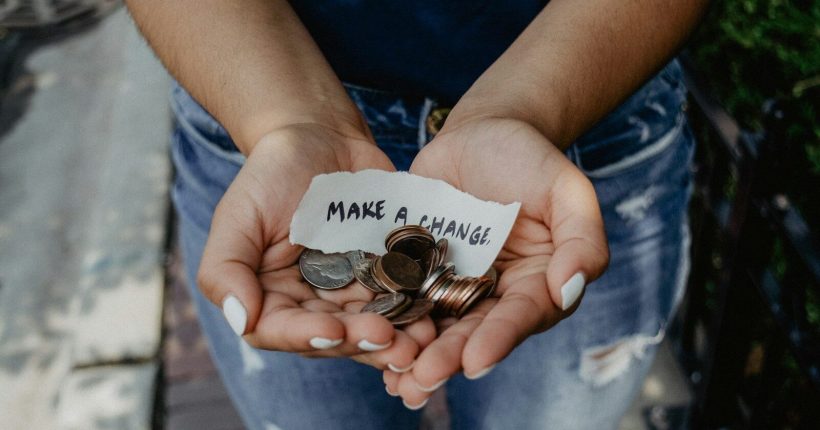 person showing both hands with make a change note and coins