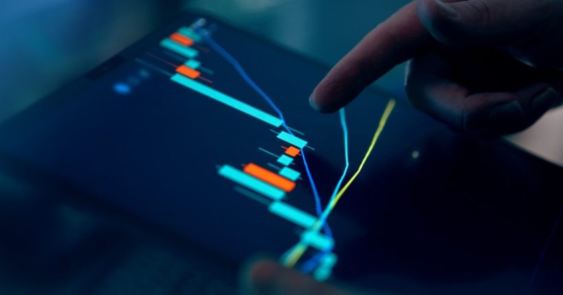 Fingers interacting with a stock market graph on a tablet.
