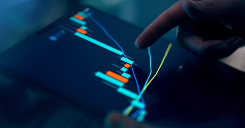 Fingers interacting with a stock market graph on a tablet.
