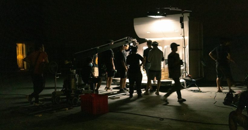 a group of people standing around a camera in the dark