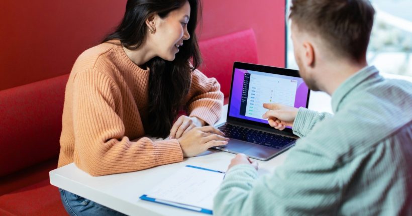 a man and a woman sitting at a table with a laptop