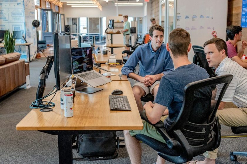 three men sitting on chair beside tables