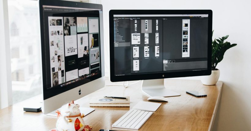 two imac s with keyboard and phones on desk