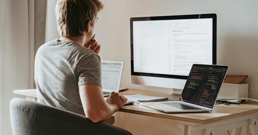 man sitting in front of three computers