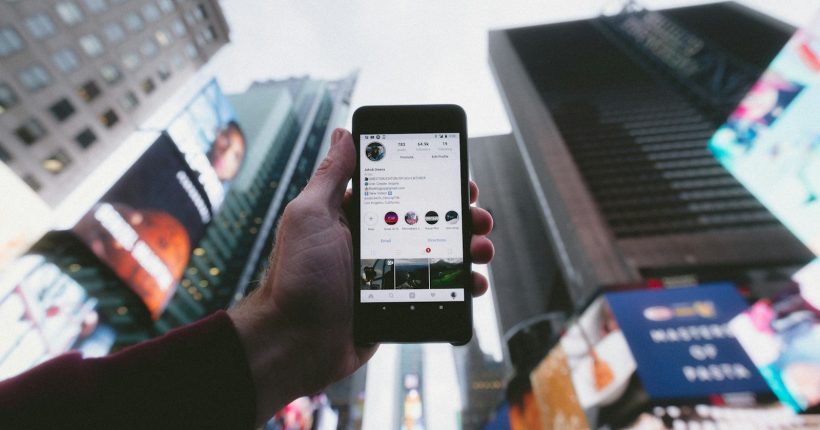high angle photo of person holding turned on smartphone with tall buildings background