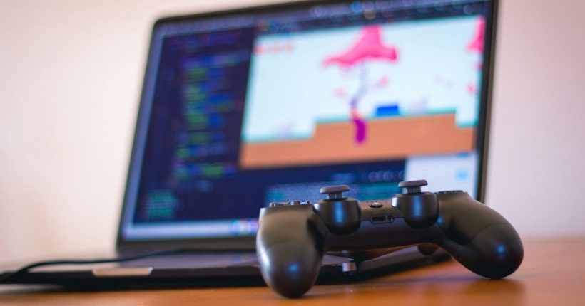 black laptop computer beside controller on brown wooden surface